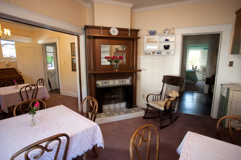 The breakfast room, with lace-covered tables beside a tiled fireplace