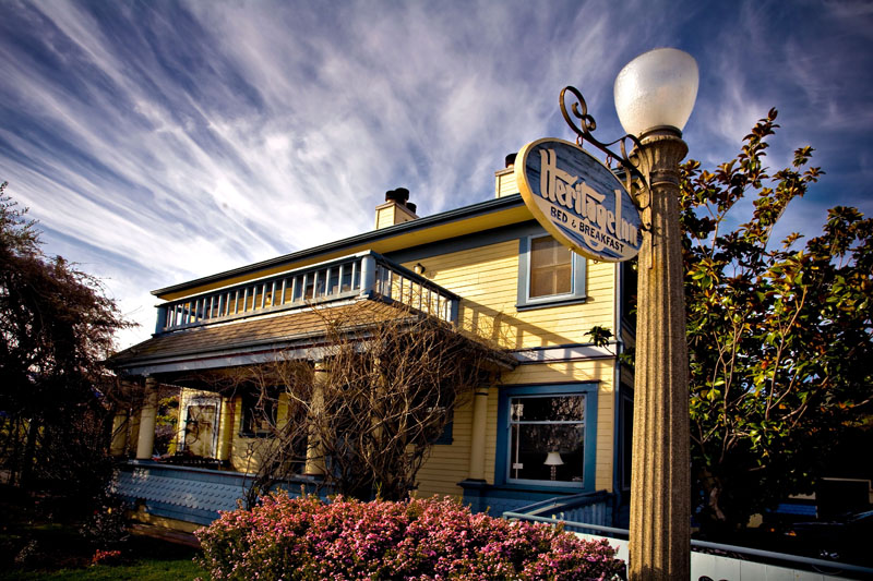 The Heritage Inn, a yellow two-storey house with a wraparound porch and the inn's hanging sign